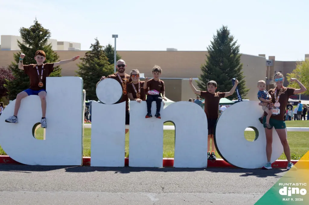 Family of runners posing in front of big dino letters
